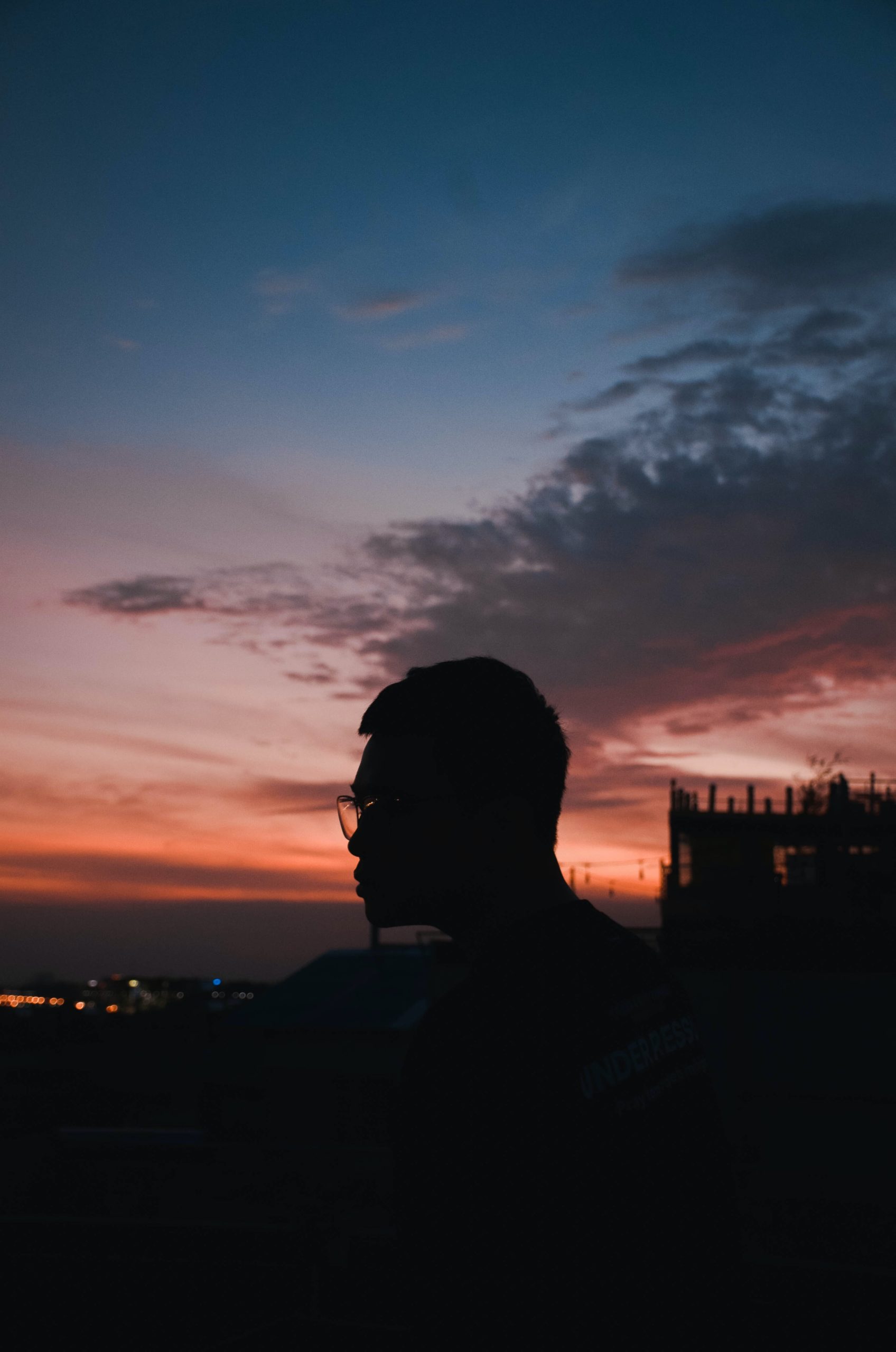Man wearing glasses on rooftop looking at sunset